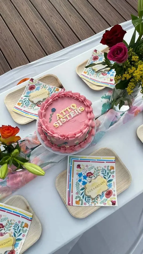 A table set for an ATTQ sisters social, with flowers and a cake